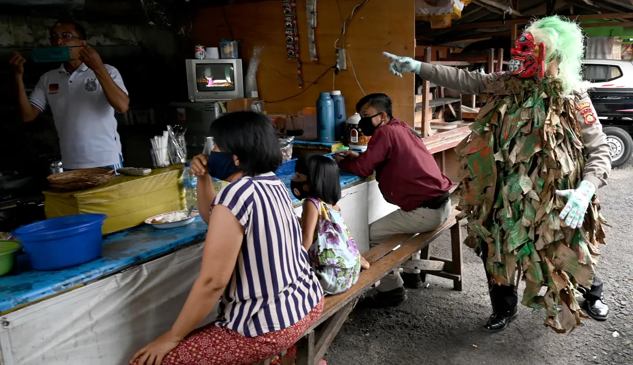 Polisi mengenakan topeng menyeramkan yang disebut "Leak" saat sosialisasi langkah-langkah pencegahan COVID-19 di pasar tradisional di Kerobokan, Denpasar, Kamis (14/5/2020). Kegiatan itu untuk mengimbau masyarakat terus melakukan berbagai upaya pencegahan penyebaran COVID-19. (SONNY TUMBELAKA/AFP)