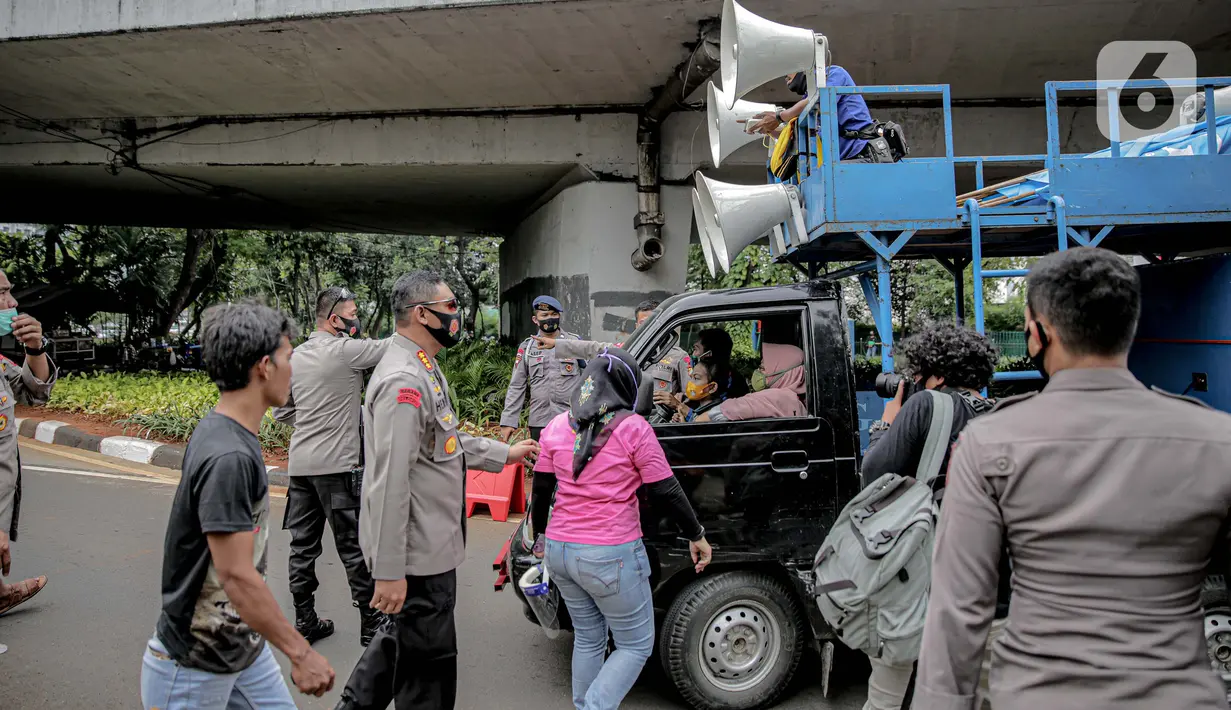 Petugas kepolisian yang berjaga memberhentikan mobil komando aksi di sekitar Gedung DPR, Jakarta, Jumat (14/8/2020). Polda Metro Jaya melarang adanya unjuk rasa di depan Gedung DPR/MPR yang bertepatan dengan sidang tahunan sekaligus pidato kenegaraan Presiden Jokowi. (Liputan6.com/Faizal Fanani)