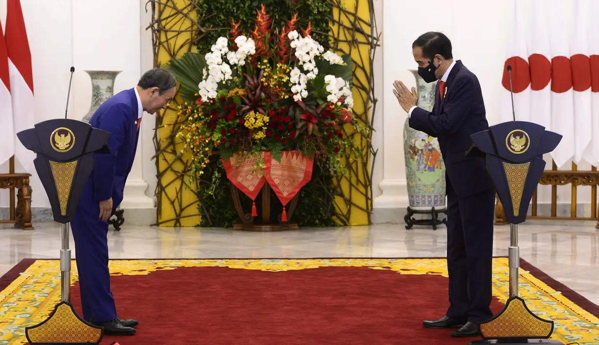 Perdana Menteri Jepang Yoshihide Suga (kiri) dan Presiden Joko Widodo (Jokowi) saling menyapa saat konferensi pers bersama di Istana Bogor, Selasa (20/10/2020). Lawatan kenegaraan tersebut dalam rangka meningkatkan hubungan bilateral antar kedua negara. (INDONESIAN PRESIDENTIAL PALACE / AFP)