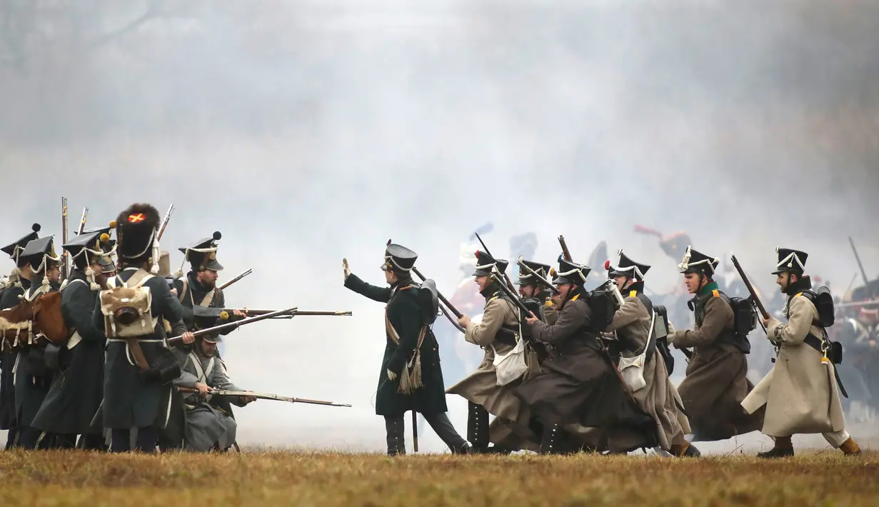 Sejumlah peserta berpakaian seperti tentara Rusia dan Prancis tahun 1812 melakukan adegan pertempuran di Belarus (26/11). Mereka melakukan reka ulang pertempuran Berezina yang terjadi pada tahun 1812.  (AP Photo/Sergei Grits)