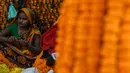 Seorang wanita membuat karangan bunga jelang Festival Diwali di pasar bunga New Delhi, India, Minggu (31/10/2021). Festival Diwali atau Festival Cahaya dalam agama Hindu melambangkan kemenangan baik atas buruk. (Money SHARMA/AFP)