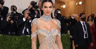 Kendall Jenner tampil bergaya ‘naked’ dalam balutan sheer gown bertabur kristal berkilau rancangan Givenchy. Penampilannya yang glamor tersebut diperlengkap dengan kalung choker besar. Model 25 tahun ini menjaga rambutnya tetap sederhana dengan sanggul rendah. (Instagram/_metgala2021).