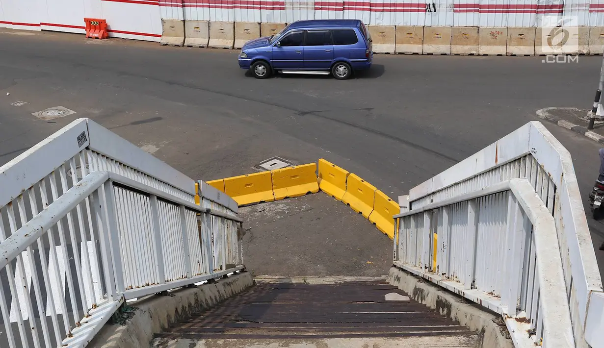 Tangga JPO di Jalan Dewi Sartika, Cawang, Jakarta Timur, berada di tengah jalan, Rabu (9/1). Adanya proyek pelebaran jalan menyebabkan posisi trotoar bergeser sehingga tangga JPO tersebut menjadi di tengah jalan. (Liputan6.com/Immanuel Antonius)