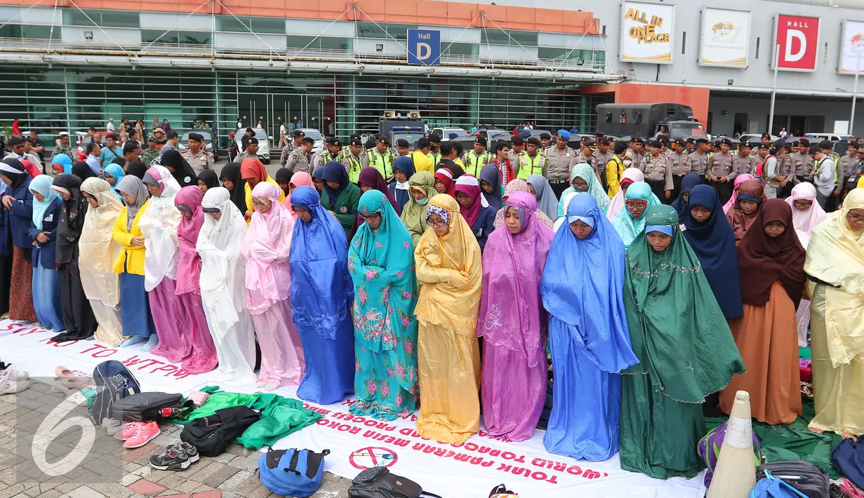Sejumlah mahasiswa melakukan salat sebelum aksi di JIEXPO, Jakarta (27/4). Mereka menolak pameran mesin rokok international karena dinilai akan berdampak pada jumlah produksi rokok dan konsumsi rokok di Indonesia. (Liputan6.com/Angga Yuniar)