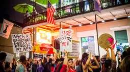 Sejumlah orang membawa poster saat melakukan demonstrasi di Bourbon Street, New Orleans (1/2). Mereka melakukan aksi terkait penggerebekan polisi dan penutupan sejumlah klub malam di Bourbon Street. (AFP/Emily Kask)