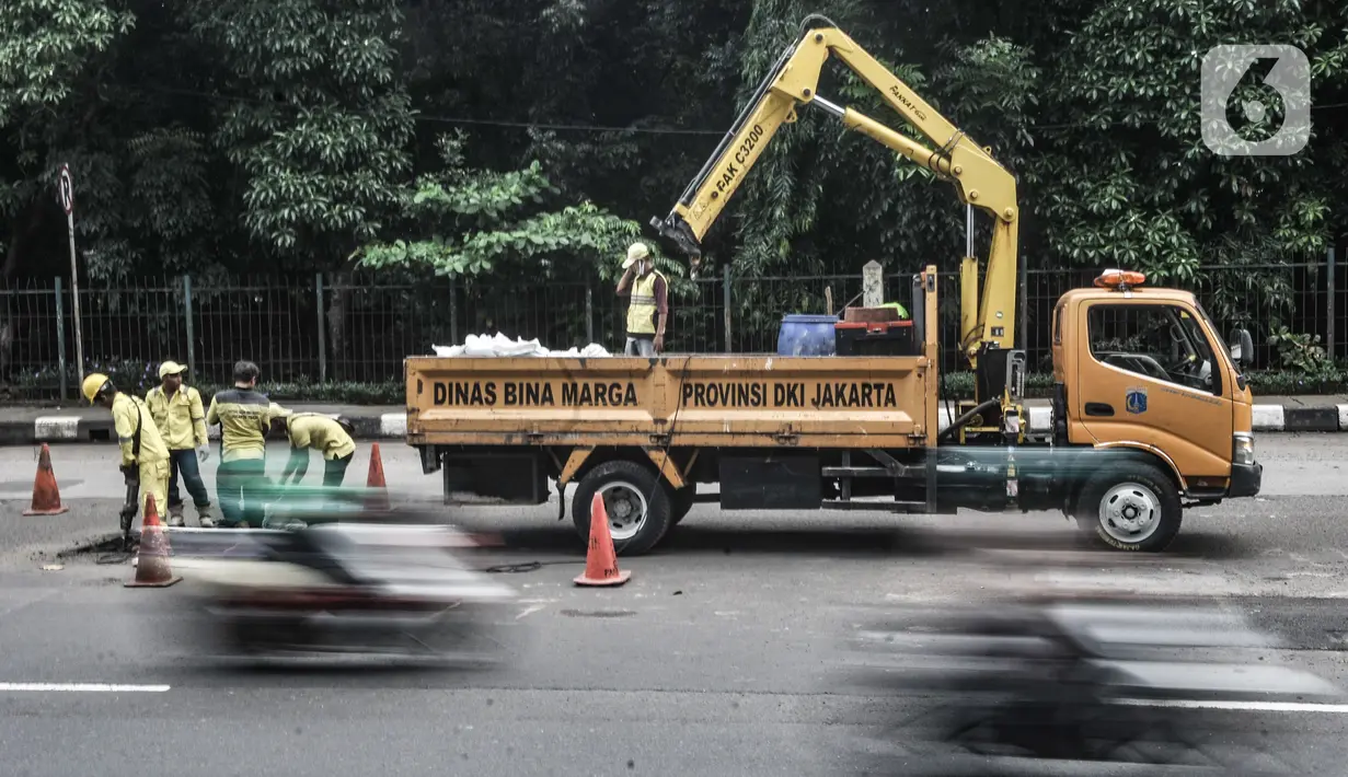 Pekerja melakukan pengaspalan jalan berlubang di Jalan DI Panjaitan, Cawang, Jakarta, Senin (25/1/2021). Perbaikan jalan rusak dan berlubang akibat sering tergenang banjir di kawasan tersebut dilakukan untuk mengantisipasi terjadinya kecelakaan pengendara. (merdeka.com/Iqbal S Nugroho)