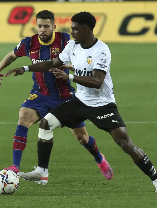 Bek Barcelona, Jordi Alba berusaha merebut bola dari pemain Valencia, Thierry Correia pada pertandingan La Liga Spanyol di stadion Mestalla, Senin (3/5/2021). Kemenangan ini menjaga peluang juara Barcelona musim ini. Mereka masih ada di peringkat ketiga dengan 74 poin. (AP Photo/Alberto Saiz)