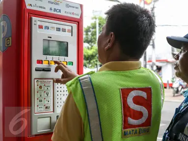 Petugas parkir melakukan transaksi dengan mesin terminal parkir elektronik (TPE) di jalan Sabang, Jakarta, Kamis (25/2). Pemprov DKI Jakarta berencana menambah mesin terminal parkir elektronik (TPE) atau parkir meter. (Liputan6.com/Yoppy Renato)