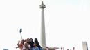 Pengunjung saat berswafoto dengan latar Tugu Monas, Jakarta. (Liputan6.com/Angga Yuniar)