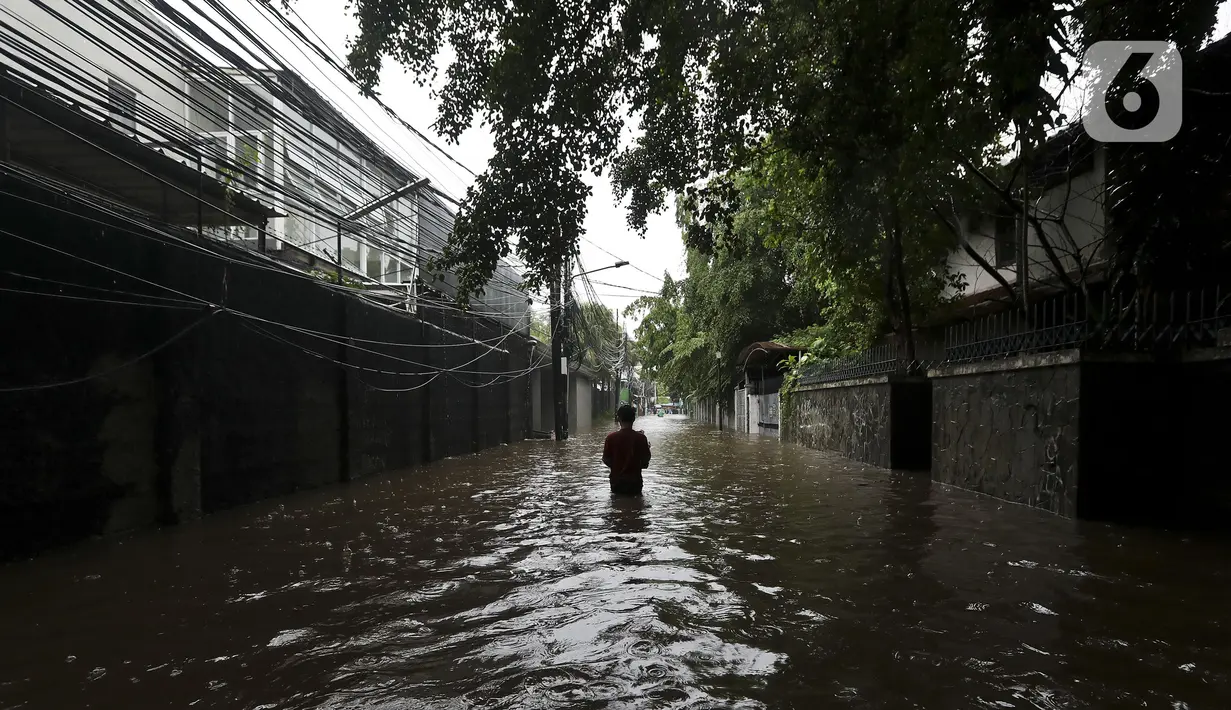Warga melintasi banjir di Jalan Hang Lekir, Kebayoran Lama, Jakarta Selatan, Rabu (1/1/2020). Banjir tersebut disebabkan karena tingginya intensitas hujan yang mengguyur sejak Selasa (31/12/2019). (Liputan6.com/Johan Tallo)