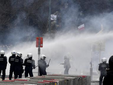 Polisi menembakkan water cannon ke arah pengunjuk rasa saat demonstrasi menentang tindakan Covid-19 di Brussel, Minggu (23/1/2022). Pengunjuk rasa berkumpul di ibu kota Belgia mengkritik dan menolak aturan pembatasan akibat COVID-19, salah satunya terkait vaksinasi. (AP Photo/Geert Vanden Wijngaert)