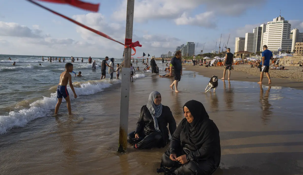 Dua wanita Palestina saat menikmati pesisir pantai laut Mediterania di Tel Aviv, Israel. (AP Photo/Oded Balilty)