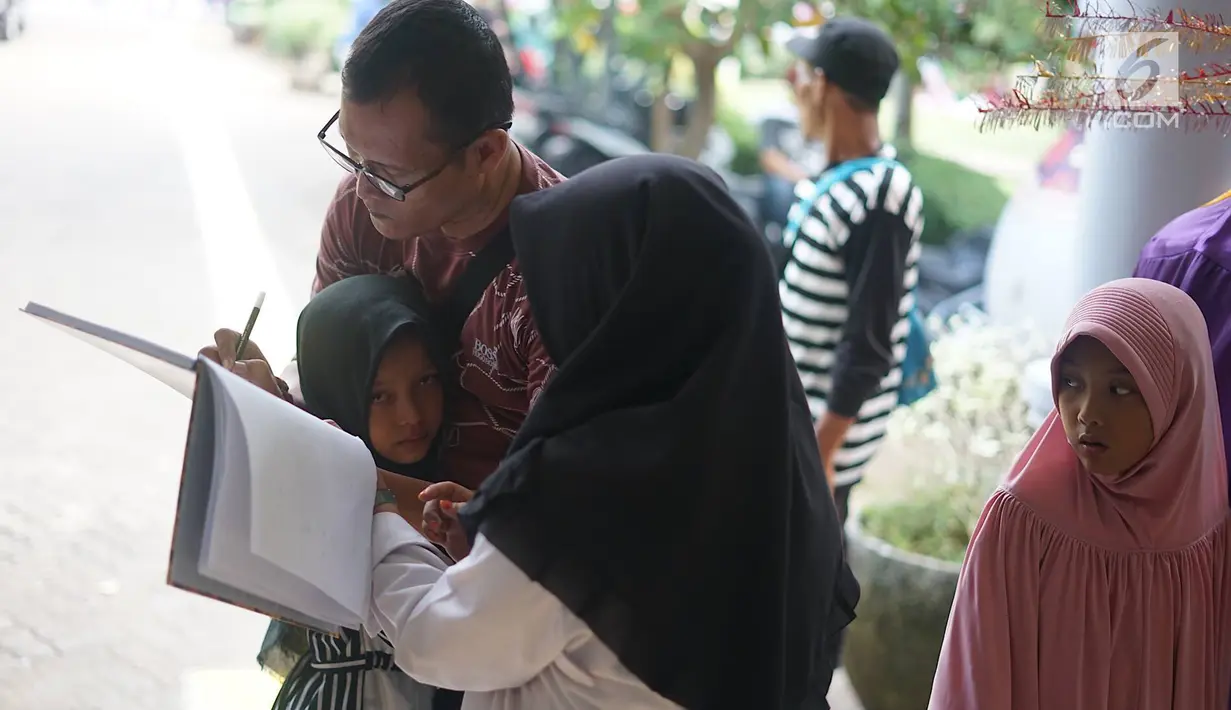 Seorang ayah mengisi data informasi setelah bertemu anaknya yang sempat hilang di Taman Margasatwa Ragunan, Jakarta, Kamis (6/6/2019). Membeludaknya pengunjung, membuat banyak orang yang memadati pusat informasi untuk mencari anggota keluarga serta barang berharga. (Liputan6.com/Immanuel Antonius)