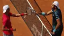 Petenis Argentina Federico Coria dan petenis Italia Matteo Berrettini bersalaman dengan cara mengetuk raket di akhir pertandingan Italia Open di Foro Italico, Rabu (16/9/2020). (AFP/Clive Brunskill/pool)