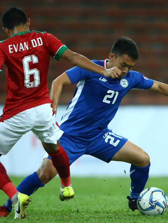 Gelandang Timnas Indonesia U-22, Evan Dimas Darmono berusaha merebut bola dari pemain Filipina, Jeremiah Borlongan pada laga SEA Games di Stadion Shah Alam, Selangor (17/8). Indonesia menang 3-0 atas Filipina. (AP Photo / Vincent Phoon)
