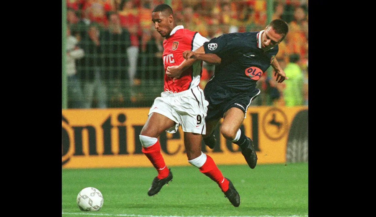 Striker Arsenal, Nicolas Anelka (kiri) berebut bola dengan bek RC Lens, Frederic Dehu pada laga penyisihan grup Liga Champions 1998/1999 di Lens, Prancis (16/9/1998). Nicolas Anelka yang telah pensiun sebagai pemain pada Januari 2016 bersama Mumbai City, tercatat pernah berseragam Arsenal selama 2,5 musim mulai tengah musim 1996/1997 hingga akhir musim 1998/1999. Gelar PFA Young Player of the Year diraihnya di musim terakhirnya pada 1998/1999. (AFP/Denis Charlet)