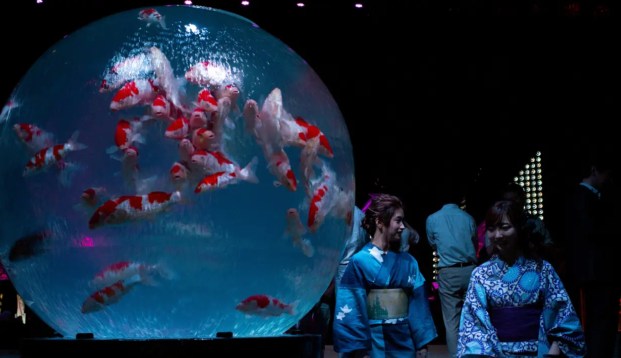 Dua wanita mengenakan kimono melihat ikan mas saat pratinjau pers dari pameran EDO Nihonbashi Art Aquarium 2018 di Tokyo, Jepang (5/7). Pameran tersebut menampilkan sekitar ribuan ikan mas. (AFP Photo/Martin Bureau)