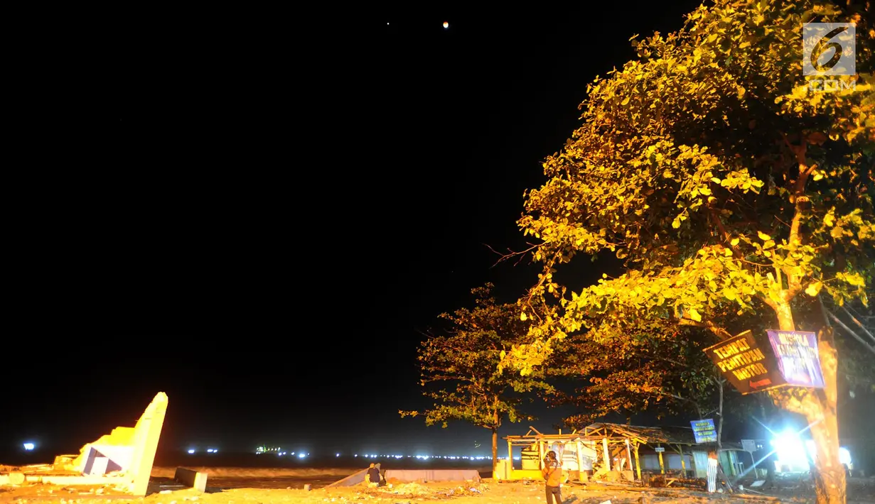 Warga menyaksikan pemandangan planet Mars berdampingan dengan gerhana bulan total terlihat di Karang Hawu, Pelabuhan Ratu, Sukabumi, Sabtu (28/7) dini hari. Fenomena alam ini menjadi gerhana Bulan paling lama Abad 21.  (Merdeka.com/Arie Basuki)