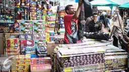 Seorang pedagang membungkus petasan yang sudah laku di Pasar Asemka, Jakarta, Selasa (27/12). ). Biasanya, perayaan tahun baru memang identik dengan menyalakan petasan dan pesta kembang api. (Liputan6.com/Faizal Fanani)
