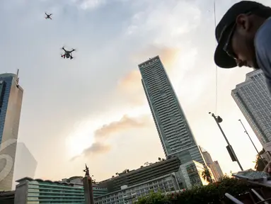 Seorang pilot drone saat menerbangkan drone di Bundaran HI, Jakarta, Kamis(28/5/2015). Penggunaan pesawat terbang tanpa awak atau yang sering disebut sebagai drone mulai dilarang di beberapa negara. (Liputan6.com/Faizal Fanani)