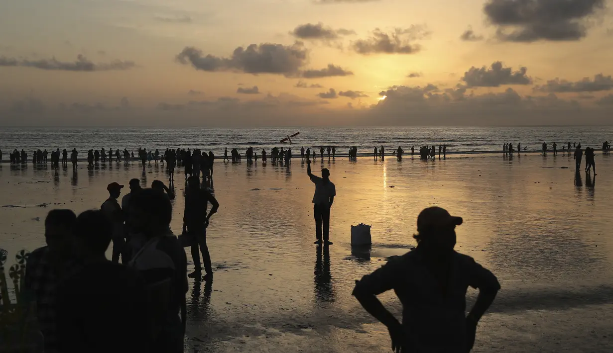 Orang-orang menyaksikan matahari terbenam di Pantai Juhu, Mumbai, India, Selasa (24/8/2021). India mencatat penambahan 14.419 kasus positif COVID-19 pada 24 Agustus 2021. (AP Photo/Rafiq Maqbool)