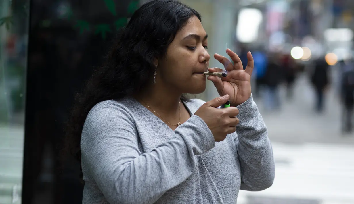 Pelanggan mengisap ganja yang dijual bebas di toko Weed World di New York (31/3/2021). Pengesahan tersebut dibuat setelah Gubernur New York Andrew Cuomo menandatangani undang-undang yang melegalkan ganja pada 31 Maret 2021. (AFP/Kena Betancur)