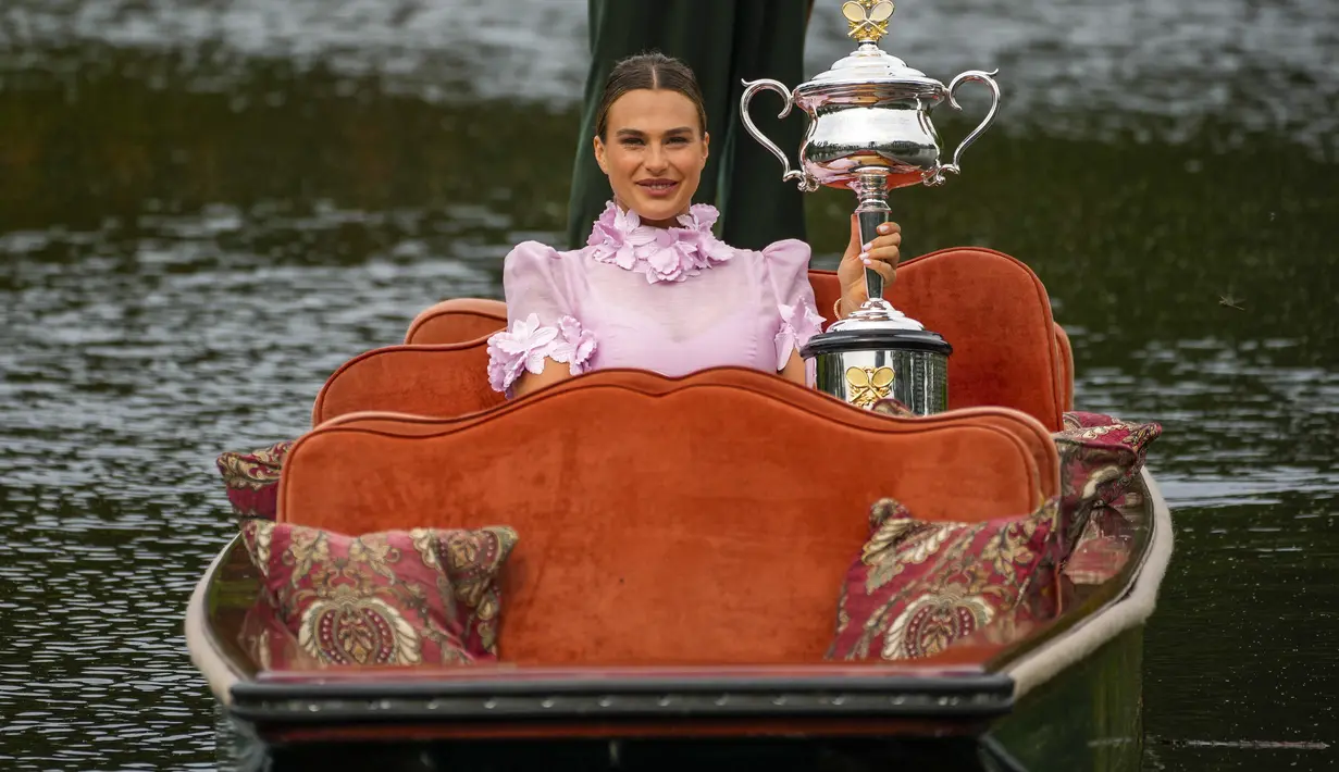 Aryna Sabalenka dari Belarusia berpose dengan trofi kejuaraan tenis Australia Open 2023 di atas gondola di Royal Botanic Garden di Melbourne (29/1/2023). Kemenangan ke-11 berturut-turut tahun ini juga membawa Sabalenka kembali ke peringkat kedua WTA di belakang Iga Swiatek dari Polandia. (AP Photo/Aaron Favila)