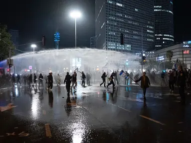 Polisi menembakkan meriam air untuk membubarkan demonstran yang memblokir jalan selama protes menentang rencana pemerintah Perdana Menteri Benjamin Netanyahu untuk melakukan reformasi peradilan di Tel Aviv, Israel, Senin (27/3/2023). (AP Photo/Oded Balilty)