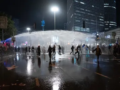 Polisi menembakkan meriam air untuk membubarkan demonstran yang memblokir jalan selama protes menentang rencana pemerintah Perdana Menteri Benjamin Netanyahu untuk melakukan reformasi peradilan di Tel Aviv, Israel, Senin (27/3/2023). (AP Photo/Oded Balilty)