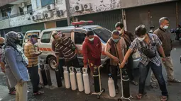 Warga mengantre untuk mengisi ulang tabung oksigen di stasiun pengisian di kota Surabaya, Kamis (15/7/2021). Di Surabaya, masih banyak permintaan isi ulang oksigen, baik tabung kecil 0,5–1 meter kubik hingga ukuran besar 6–7 meter kubik. (Juni Kriswanto / AFP)