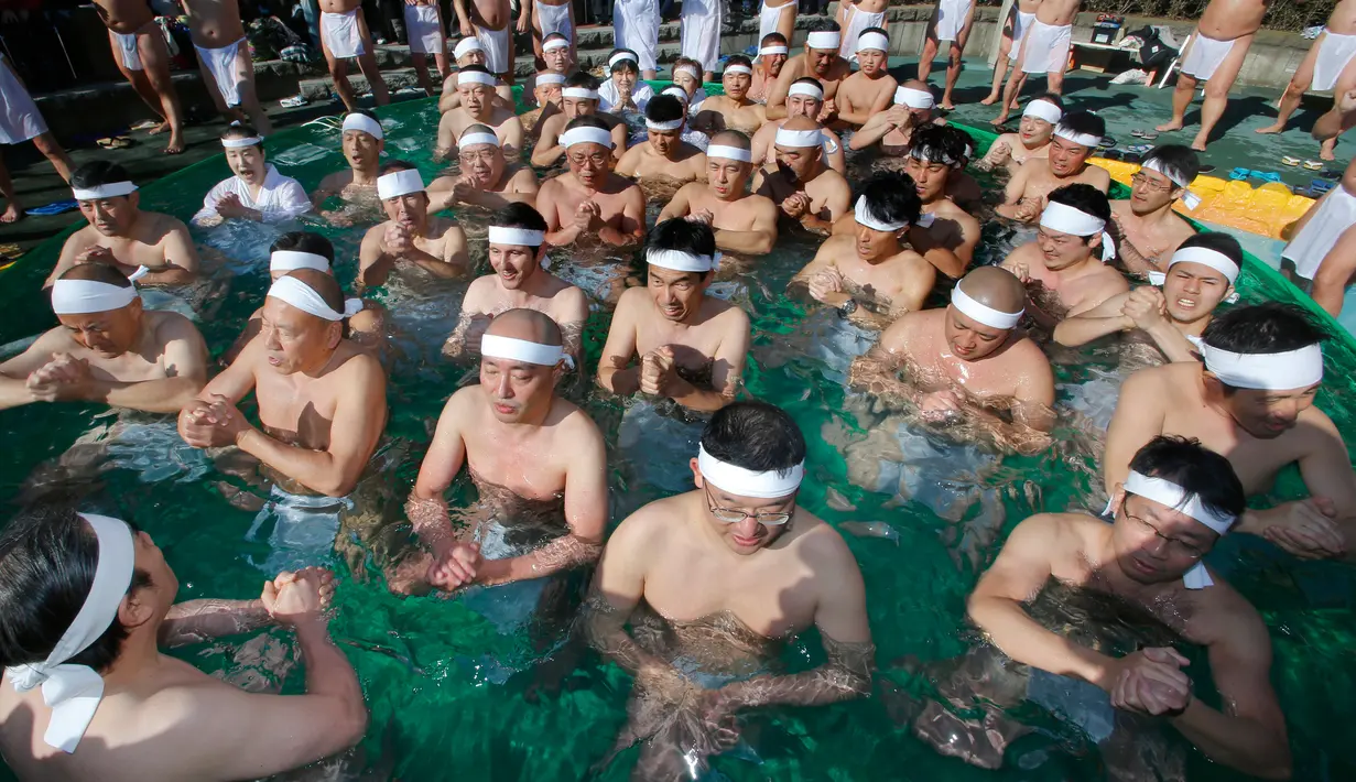Sejumlah peserta berendam di dalam kolam air dingin di Teppozu Inari Shinto Shrine di Tokyo, Jepang (8/1). Para pria hanya mengenakan cawat yang dimurnikan terlebih dahulu dengan doa dari pemimpin agama. (AP Photo/Shizuo Kambayashi)