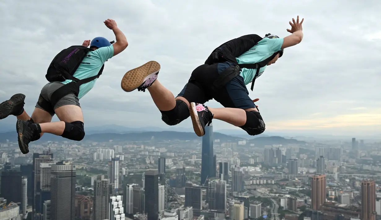 Penerjun Kanada Jeremy Bruns (kiri) dan Kelsey Fry (kanan) melompat dari dek terbuka Menara Kuala Lumpur saat International Tower Jump, Kuala Lumpur, Malaysia, 3 Februari 2023. Lebih dari 100 penerjun melompat dari Menara Kuala Lumpur setinggi 300 meter yang terkenal tersebut. (MOHD RASFAN/AFP)
