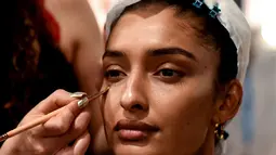Seorang model India saat dirias oleh kru makeup di belakang panggung sebelum tampil di catwalk selama Lakmé Fashion Week (LFW) Summer Resort 2019 di Mumbai, India (31/1). (AFP Photo/Sujit Jaiswal)
