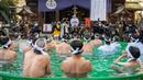 Penganut Shinto dari Kuil Teppozu Inari mandi dengan air dingin untuk mensucikan jiwa dan tubuh mereka selama ritual Tahun Baru di Tokyo, Jepang, Minggu (9/1/2022). Mereka pun satu per satu memasuki bak yang airnya dingin bahkan ada es batu di dalamnya. (Philip FONG/AFP)
