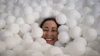 Seorang wanita tersenyum saat tenggelam dalam kolam bola putih di kantor SoHo, New York City, Selasa (25/8/2015). Tempat ini dibuat agar para karyawan dapat bermain dan dapat menhasilkan sesuatu yang kreatif. (REUTERS/Mike Segar)