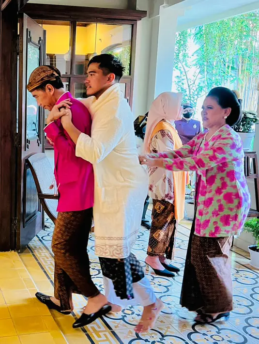 <p>Presiden Joko Widodo atau Jokowi (kiri) menggendong sang anak Kaesang Pangarep (tengah) didampingi Ibu Negara Iriana usai prosesi siraman jelang pernikahannya di kediaman, Sumber, Kota Surakarta, Jawa Tengah, Jumat (9/12/2022). Kaesang dan Erina Gudono akan melangsungkan akad nikah di Pendopo Royal Ambarrukmo Yogyakarta, Sabtu 10 Desember 2022. (Tim Media Pernikahan Kaesang-Erina)</p>