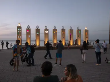 Orang-orang mengunjungi menorah Hanukkah raksasa selama hari libur Yahudi Hanukkah, di Tel Aviv, Minggu (28/11/2021). Hanukkah, juga dikenal sebagai Festival Cahaya, adalah peringatan delapan hari pemberontakan Yahudi pada abad kedua SM. (AP Photo/Oded Balilty)