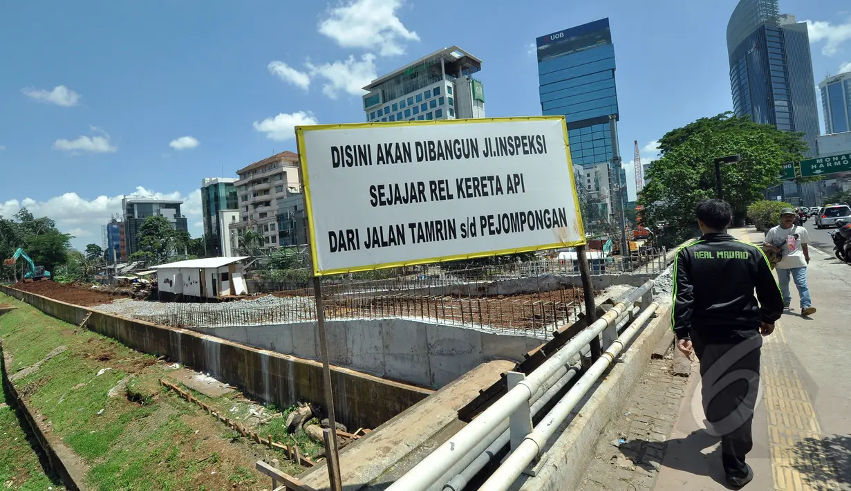 Warga melintas di depan pembangunan jalan inspeksi di Bantaran KBB kawasan Thamrin, Jakarta, Selasa (17/3/2015). Pembangunan jalan yang diproyeksikan untuk jalur alternatif bagi warga ini diperkirakan rampung pertengahan 2015. (Liputan6.com/Faizal Fanani)