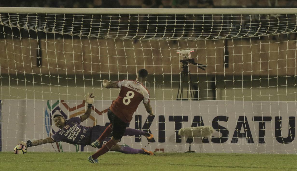 Kiper Bali United, Wawan Hendrawan, berhasil menghalau tendangan striker Madura United, Marcel Sacramento, pada laga Piala Presiden di Stadion Manahan, Solo, Sabtu, (3/2/2018). Bali United menang adu penalti dengan skor 5-4. (Bola.com/M Iqbal Ichsan)
