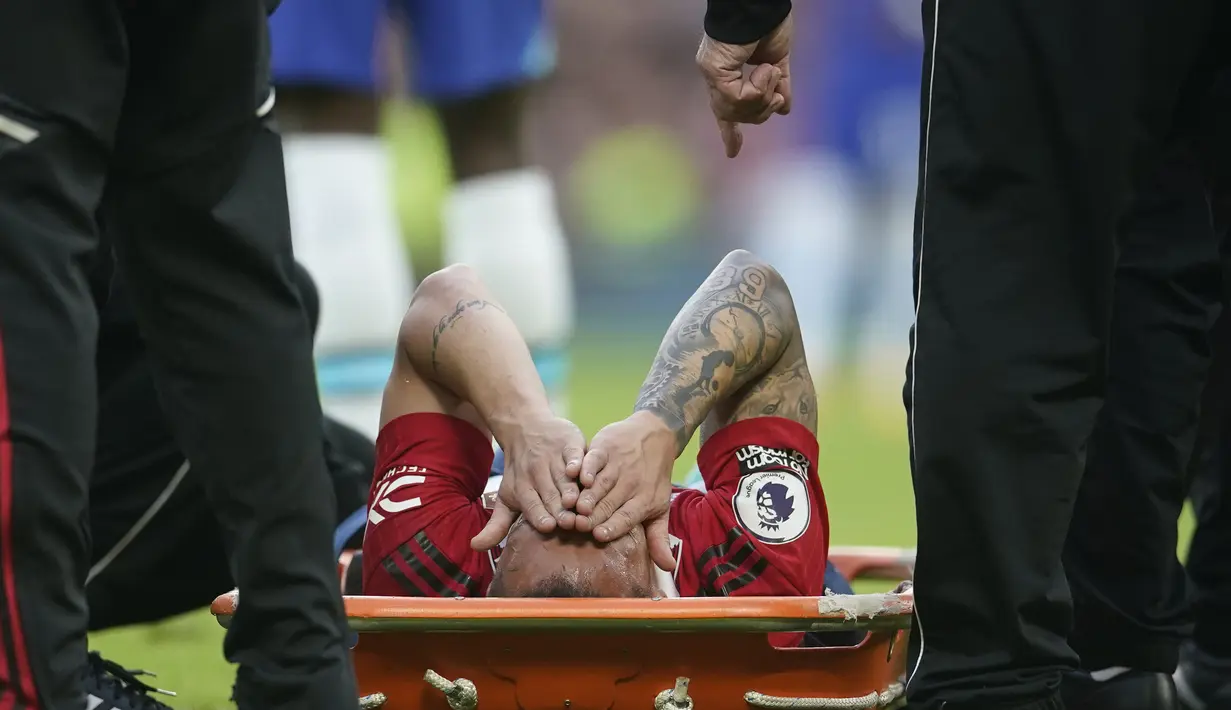 Pemain Manchester United, Antony (tengah), tidak dapat melanjutkan pertandingan dan harus ditandu keluar lapangan setelah dilanggar Pemain Chelsea dalam pertandingan partai tunda pekan ke-32 Liga Inggris 2022/2023 yang berlangsung di Old Trafford, Jumat (26/5/2023) dini hari WIB. (AP Photo/Dave Thompson)