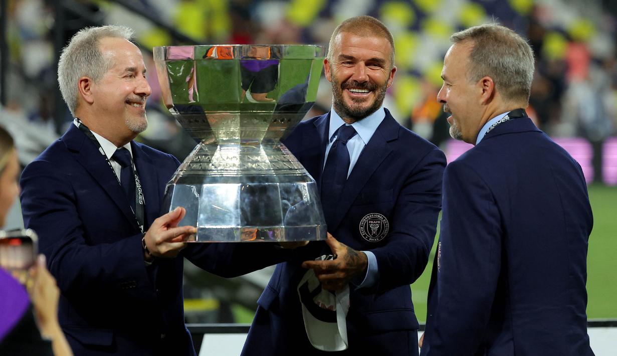 Senyum semringah pemilik bersama klub Inter Miami, David beckham (tengah), sambil memegang trofi setelah Inter Miami berhasil keluar sebagai juara di final Leagues Cup 2023 yang berlangsung di Geodis Park, Minggu (20/8/2023). Ini merupakan trofi pertama bagi Inter Miami sejak dibentuk pada lima tahun lalu. (AFP/Getty Images/Kevin C. Cox)