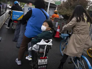 Seorang anak yang mengenakan masker duduk di belakang skuter di persimpangan di Beijing, Kamis (28/4/2022). Beijing mengalihkan lebih banyak kelas secara online pada hari Kamis dalam pengetatan pembatasan COVID-19 lebih lanjut, karena ibu kota China berupaya mencegah penyebaran yang lebih luas. (AP Photo/Mark Schiefelbein)
&nbsp;
&nbsp;