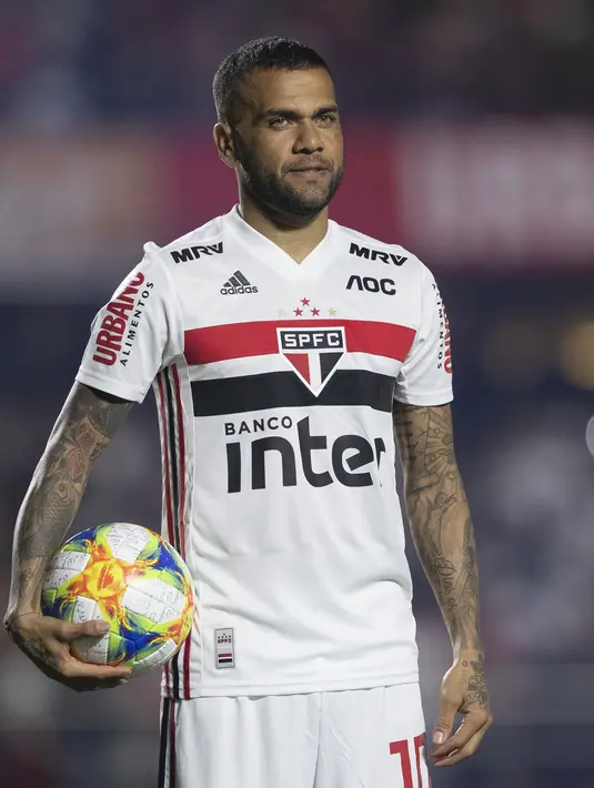 Ekspresi Dani Alves  saat diperkenalkan sebagai bek baru Sao Paulo di stadion Morumbi, Brasil (6/8/2019). Mantan pemain Barcelona dan Juventus berusia 36 tahun ini dikontrak selama tiga musim, atau hingga 2022. (AP Photo/Andre Penner)