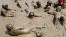 Anak-anak berendam dalam lumpur saat berpartisipasi dalam Mud Day atau Hari Lumpur di Michigan, negara bagian AS, Selasa (9/7/2019). Para peserta perayaan yang menjadi tradisi setiap tahun ini merupakan anak-anak untuk agar mereka bersenang-senang selama liburan musim panas.  (AP/Carlos Osorio)