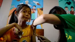 Seorang siswi meringis saat disuntikkan vaksin anti-dengue di Sekolah Dasar Parang di Marikina, sebelah barat Manila, Senin (4/4). Filipina telah menyuntikkan vaksin pertama di dunia untuk penyakit DBD itu kepada 1 juta pelajar. (NOEL CELIS/AFP)