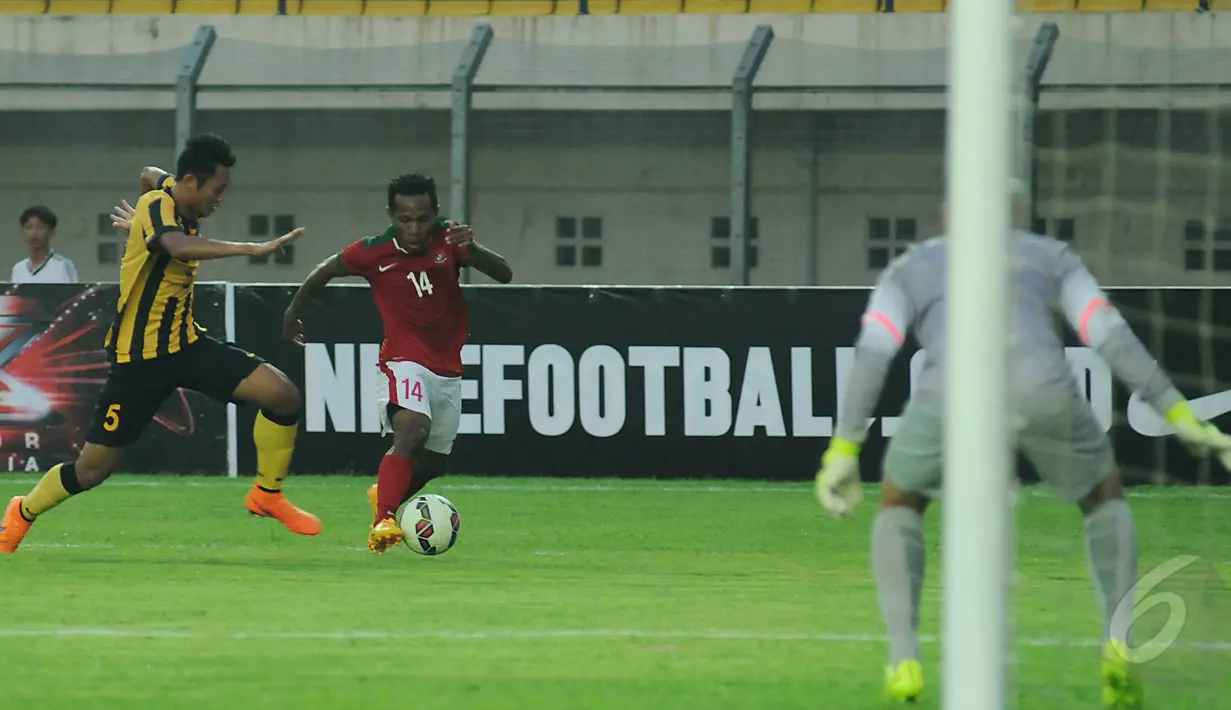 Pemain depan Timnas Indonesia U-23, Yohanes Ferinando Pahabol (14) mencoba melewati M Syazwan Tajudin (Malaysia U-23) saat laga uji coba di Stadion Si Jalak Harupat, Bandung, Kamis (21/5/2015). Indonesia unggul 1-0. (Liputan6.com/Helmi Fithriansyah)