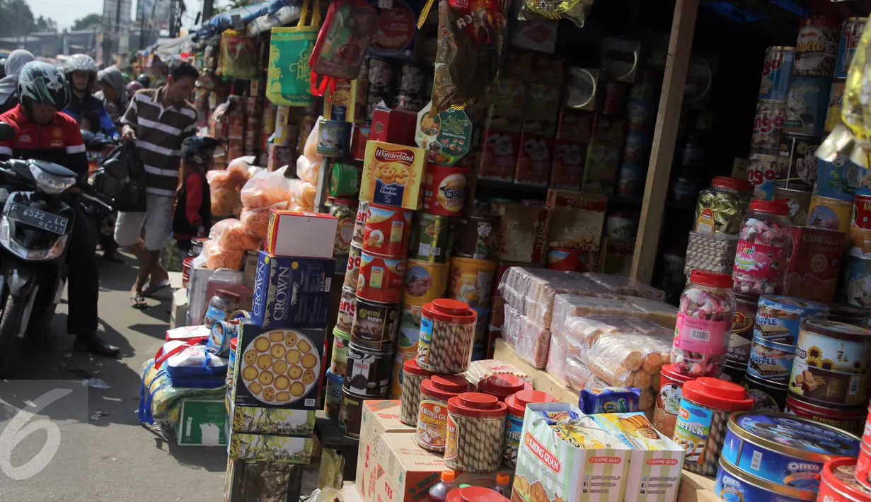 Pengendara motor membeli kue di kios penjual kue kering musiman di kawasan Ciracas, Jakarta, Minggu (12/7). Sejak beberapa hari terakhir, transaksi pedagang musiman kue kering mengalami peningkatan jelang hari raya Idul Fitri. (Liputan6.com/Helmi Afandi)