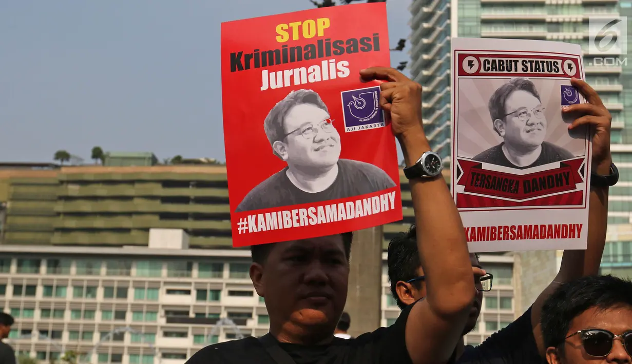 Jurnalis yang tergabung dalam Aliansi Jurnalis Independen (AJI) menunjukkan poster saat menggelar aksi pada Car Free Day di Bundaran HI, Jakarta, Minggu (29/9/2019). Polisi menjeratnya dengan UU ITE atas cuitan Dandhy soal isu Papua. (Liputan6.com/Herman Zakharia)