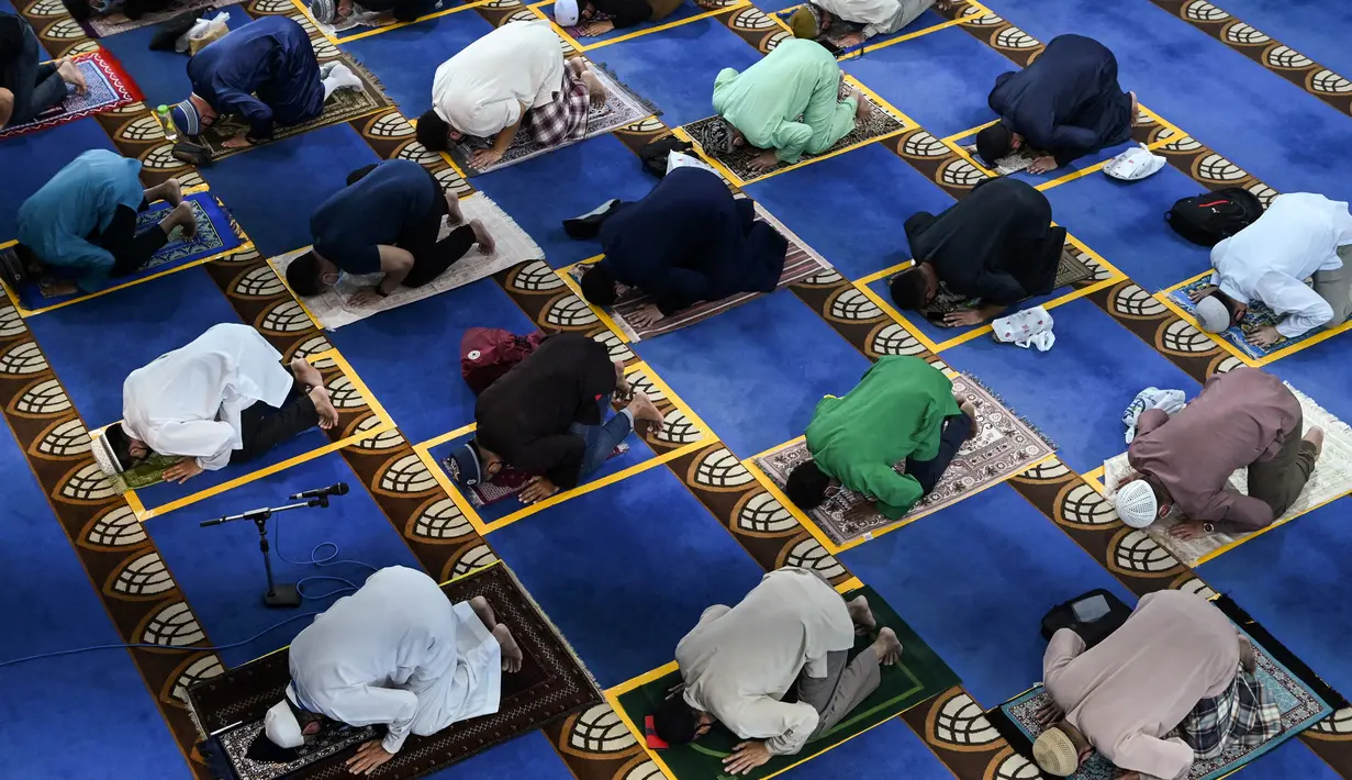 Umat muslim menjaga jarak saat salat Jumat usai pencabutan pembatasan Covid-19 di Masjid Al-Istighfar, Singapura, Jumat (26/6/2020). Masjid-masjid di Singapura telah diizinkan menggelar salat berjamaah, seiring memasuki pekan kedua dari Tahap Dua pembukaan kembali di negara itu. (Roslan RAHMAN/AFP)
