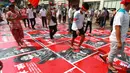 Pengunjuk rasa antikudeta menginjak poster dengan gambar seorang tentara dan tanda Burma bertuliskan "teroris bersenjata" di sebuah jalan di Yangon, Myanmar, Senin (22/2/2021). Peringatan turut diberikan dalam bahasa Inggris yang memperingatkan pendemo terhadap "kekerasan dan anarki." (AP Photo)